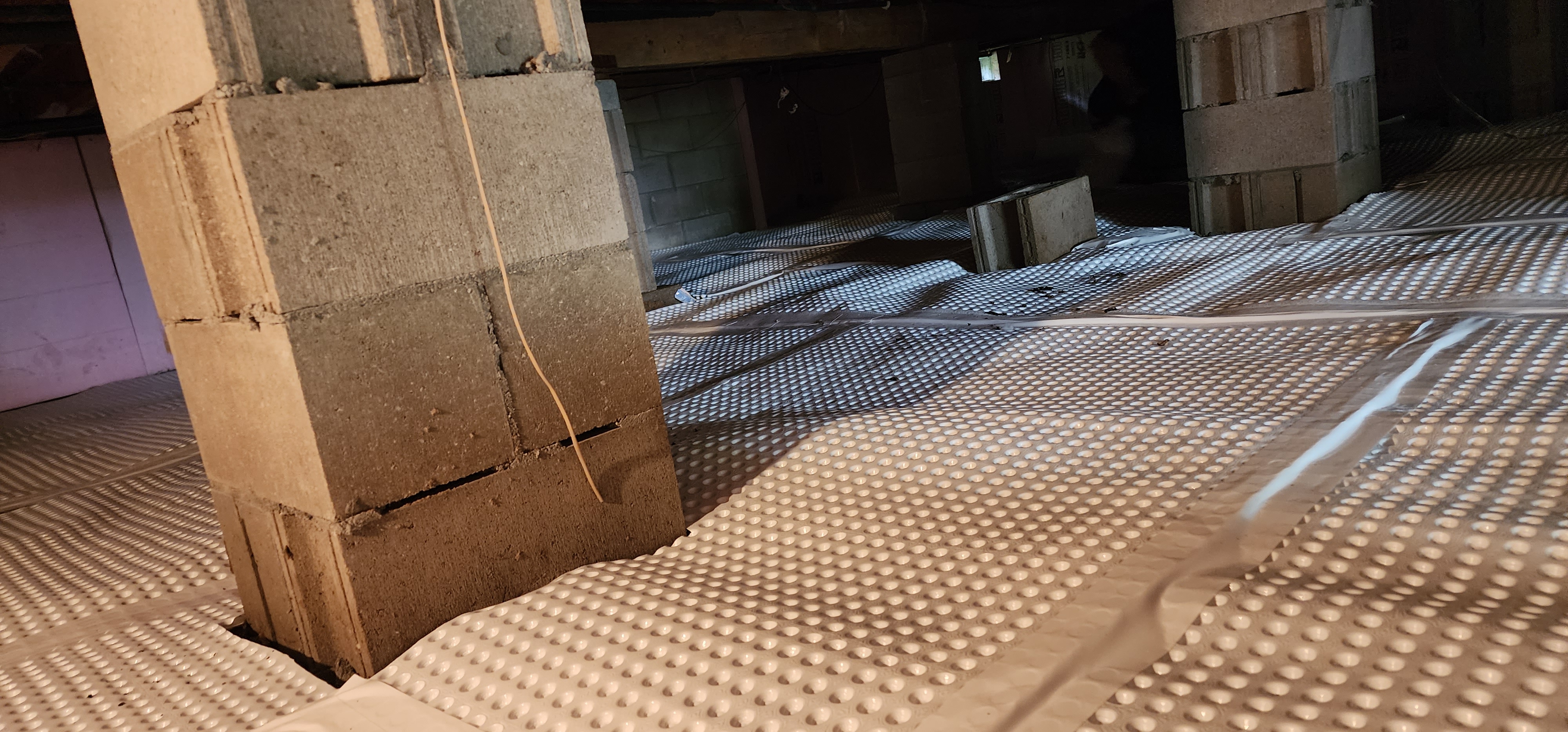 Crawlspace encapsulation process in Old Mission home showing sealed crawlspace with white vapor barrier