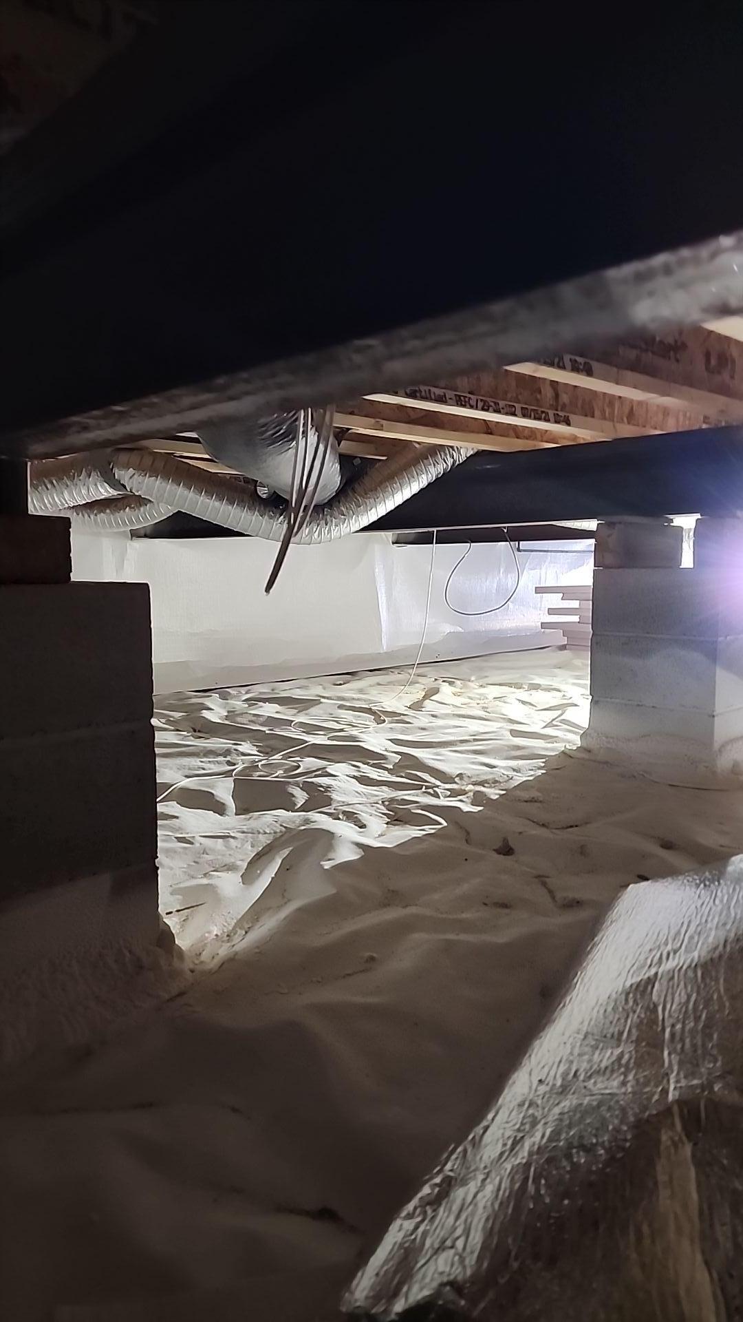 A well-encapsulated crawlspace with clean, white lining and insulation, preventing moisture and mold.