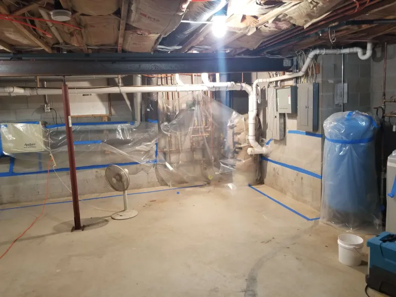 A professional waterproofing a basement to prevent future water damage in Maple City, Michigan.